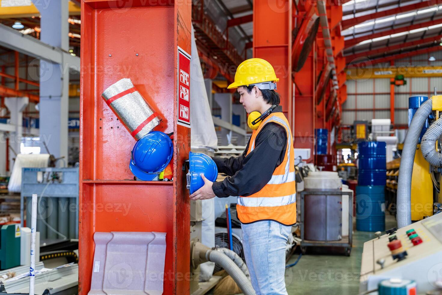 asiático trabajador es colgando su la seguridad casco en el estante dentro el pesado industrial fábrica para proteccion y accidente prevención concepto foto
