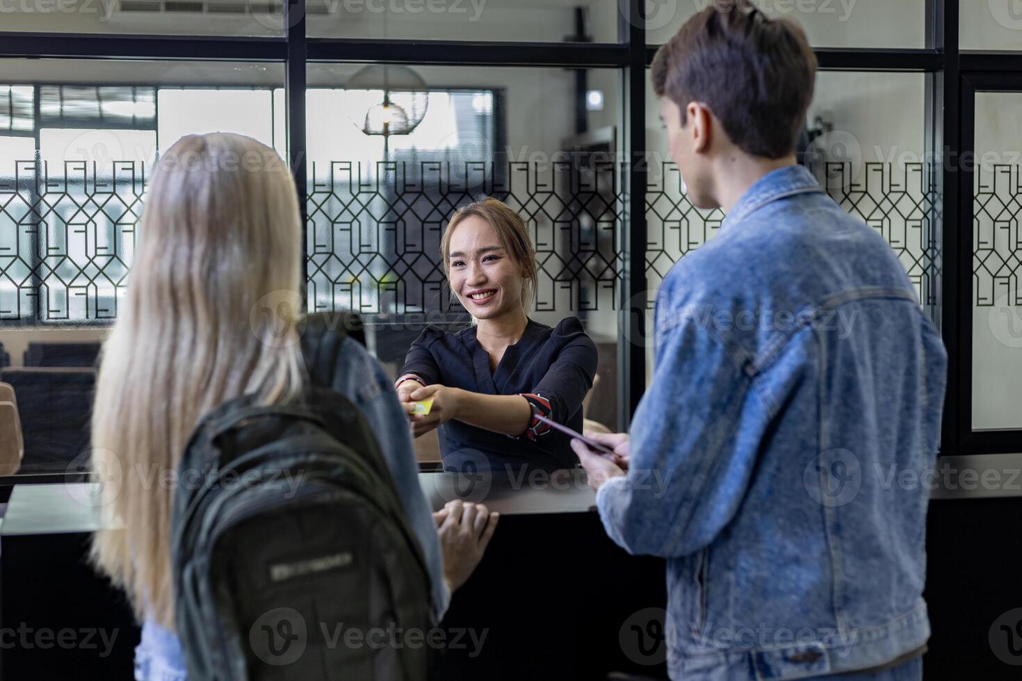 Caucasian tourist couple is handing passport to the reception at hotel lobby counter for check in to the room for international travel and vacation concept photo