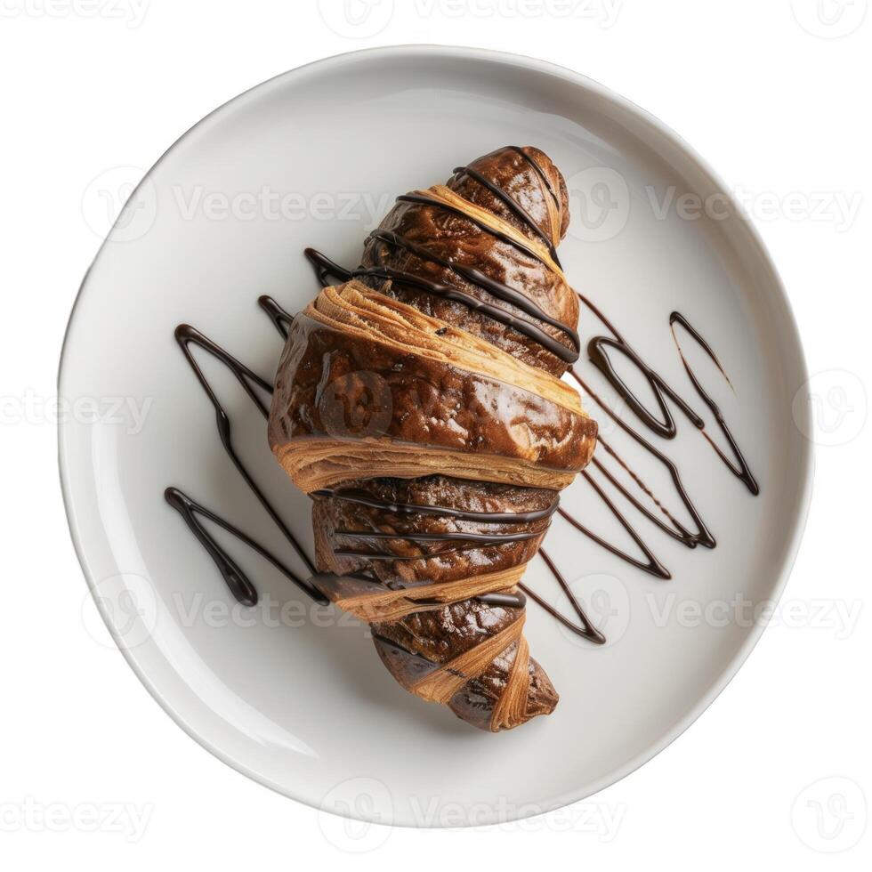French pastry A chocolate covered croissant sits on a white plate. The good bakery piece has a chocolate drizzle on top. photo