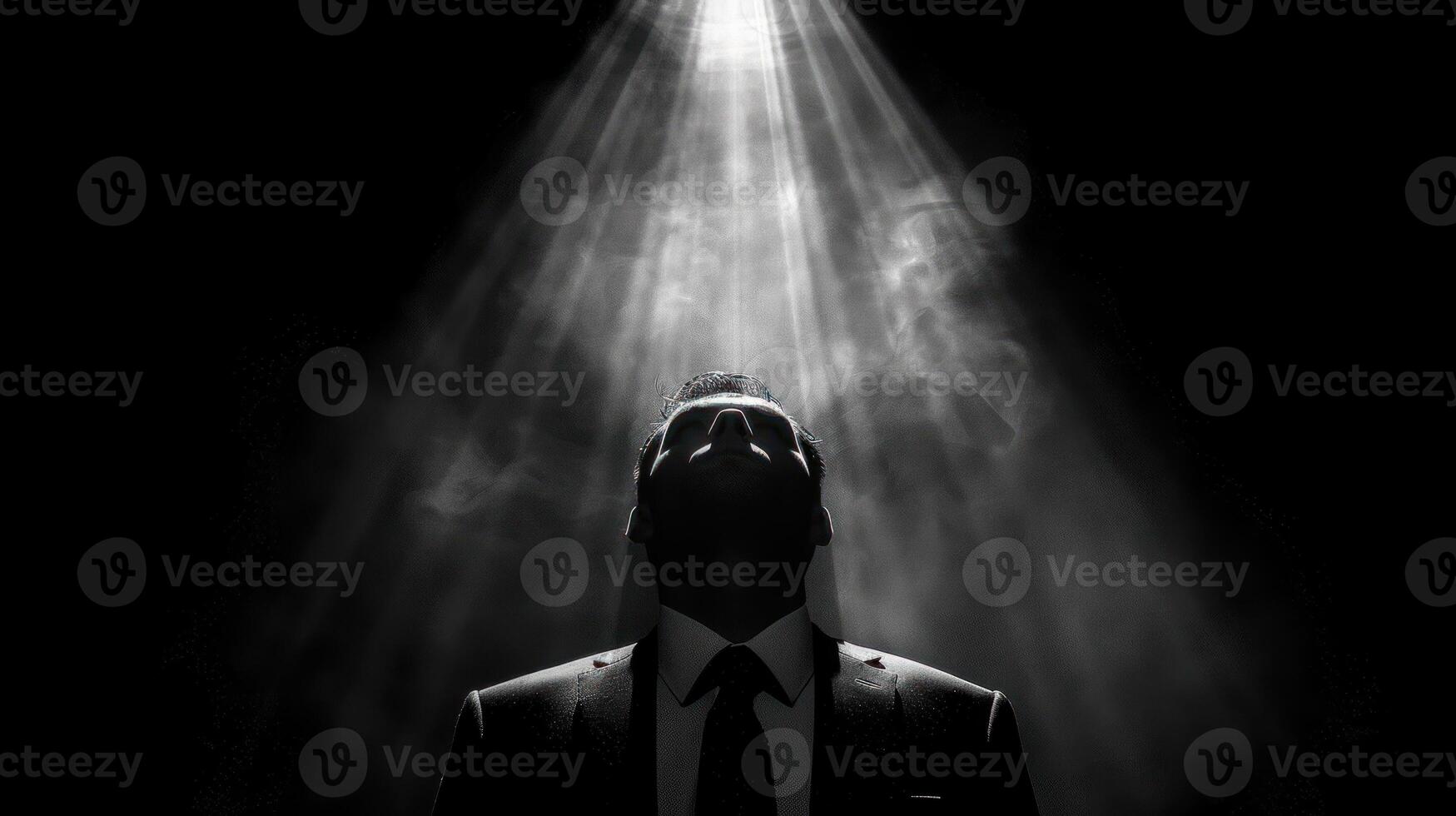 Man in business attire stands in front of bright beam of light photo