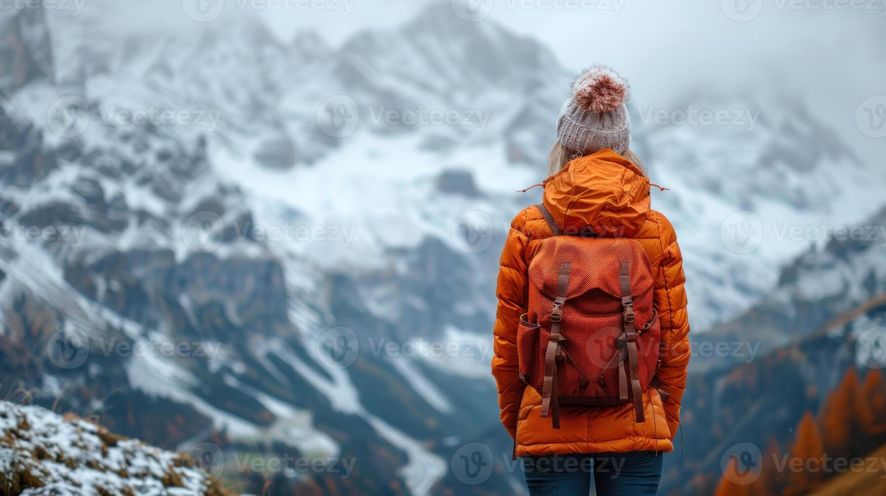 A person with a backpack stands on a mountain peak photo