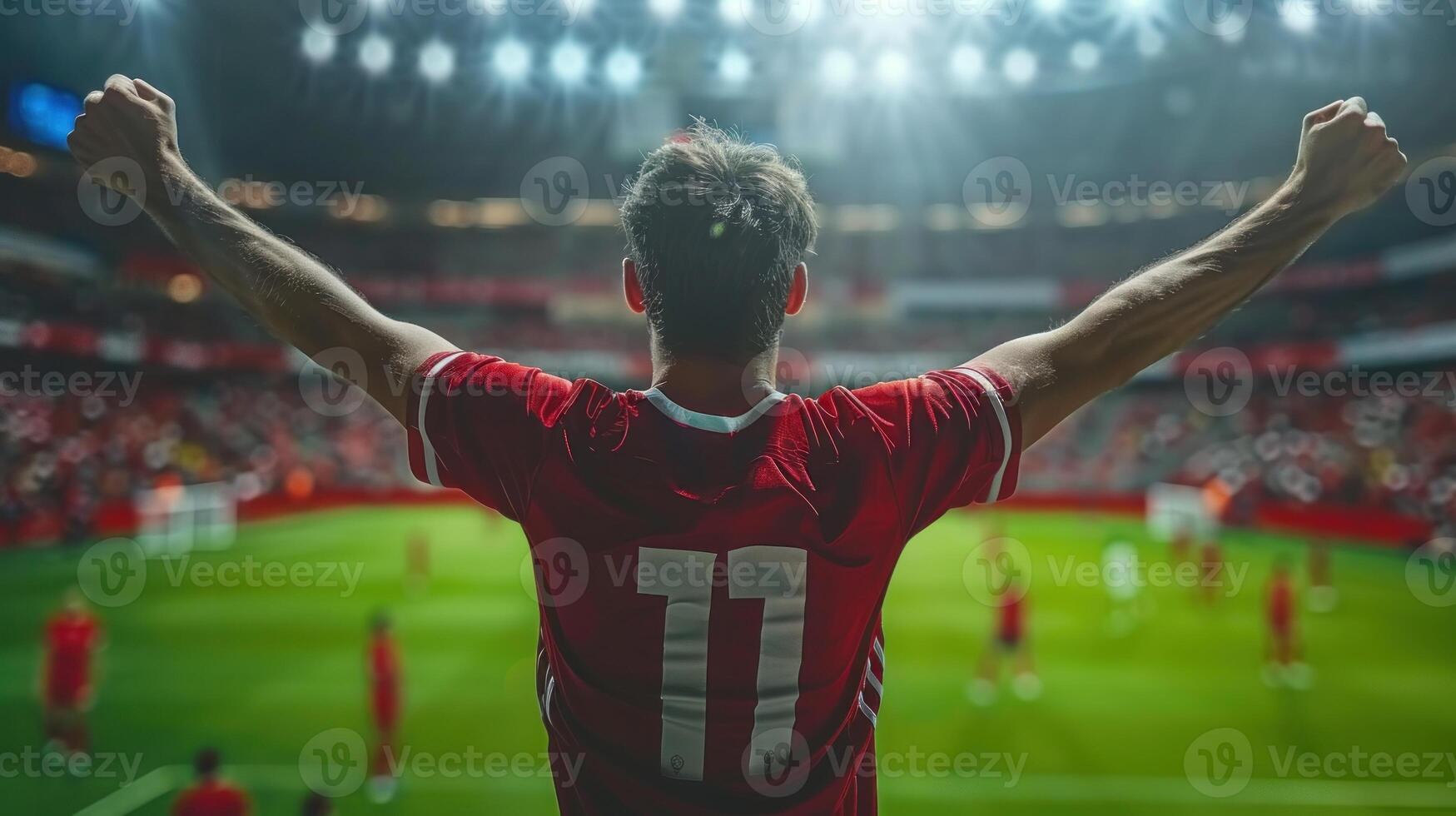A man enthusiastically celebrates with his hands up at a soccer game photo