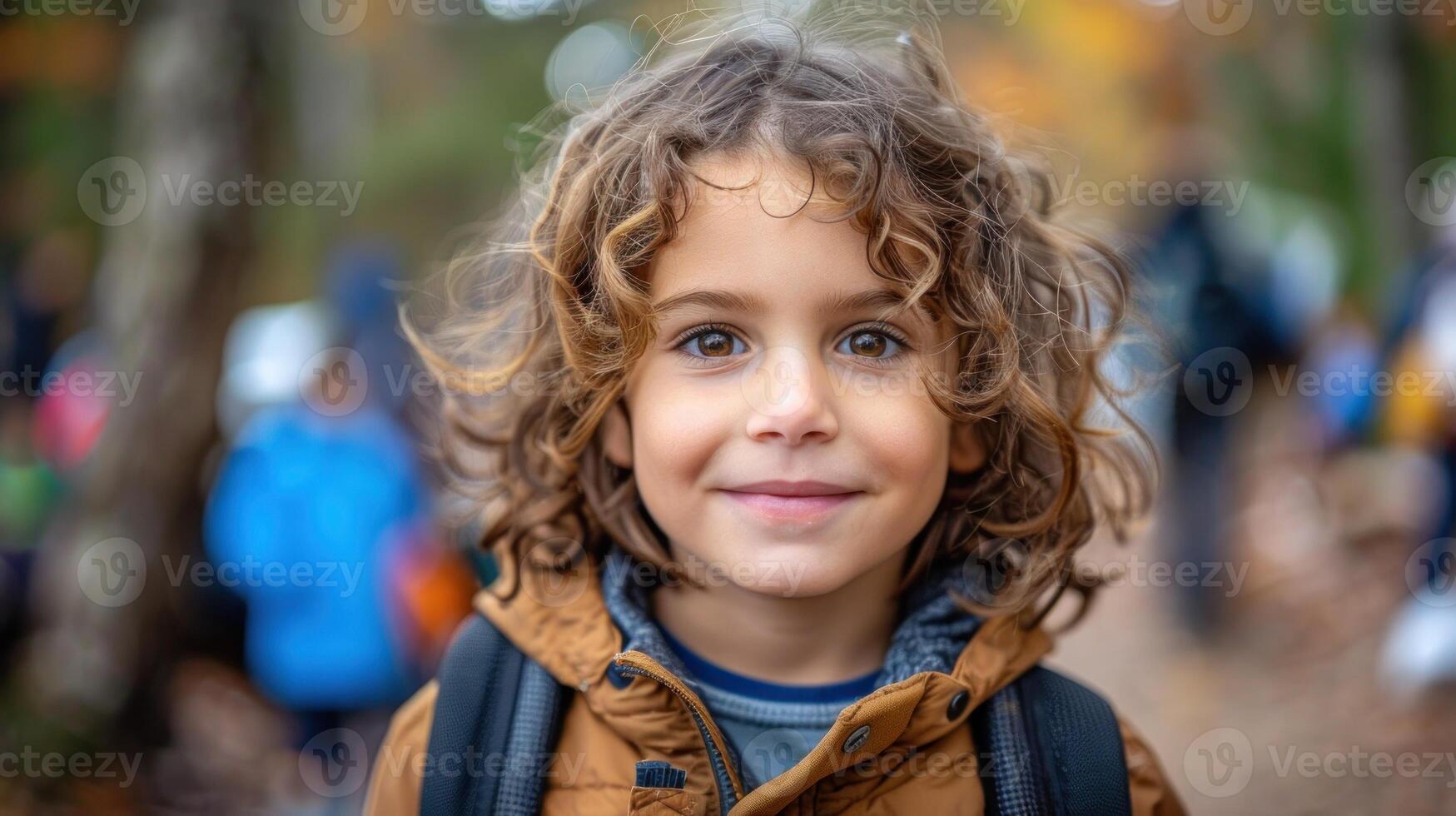 A young boy with curly hair carrying a backpack photo