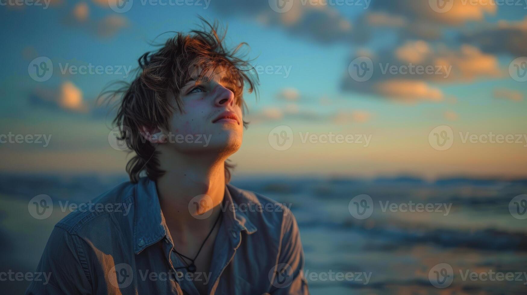 A young man gazes upwards at the sky photo