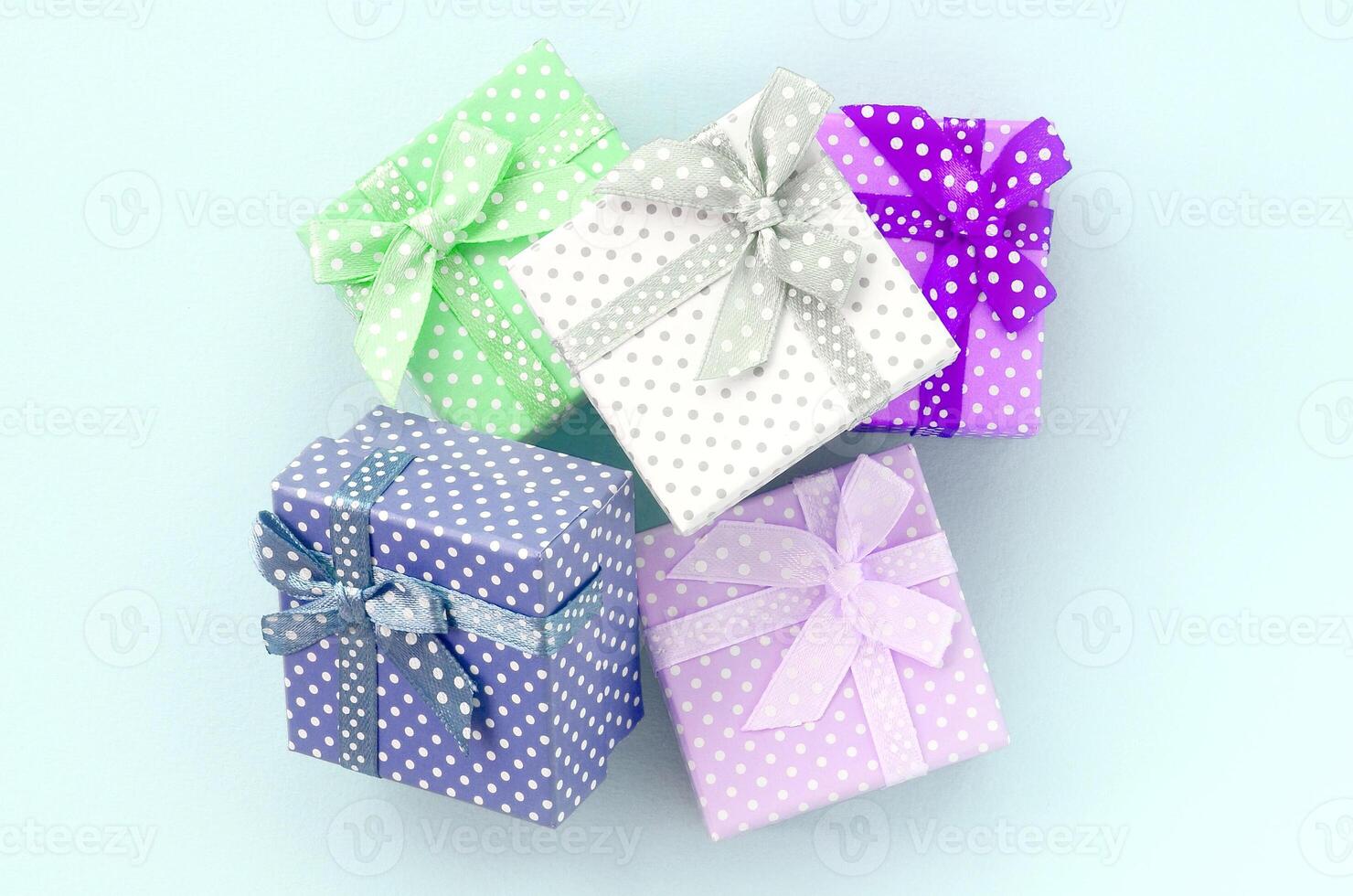 Pile of a small colored gift boxes with ribbons lies on a violet background. Minimalism flat lay top view photo