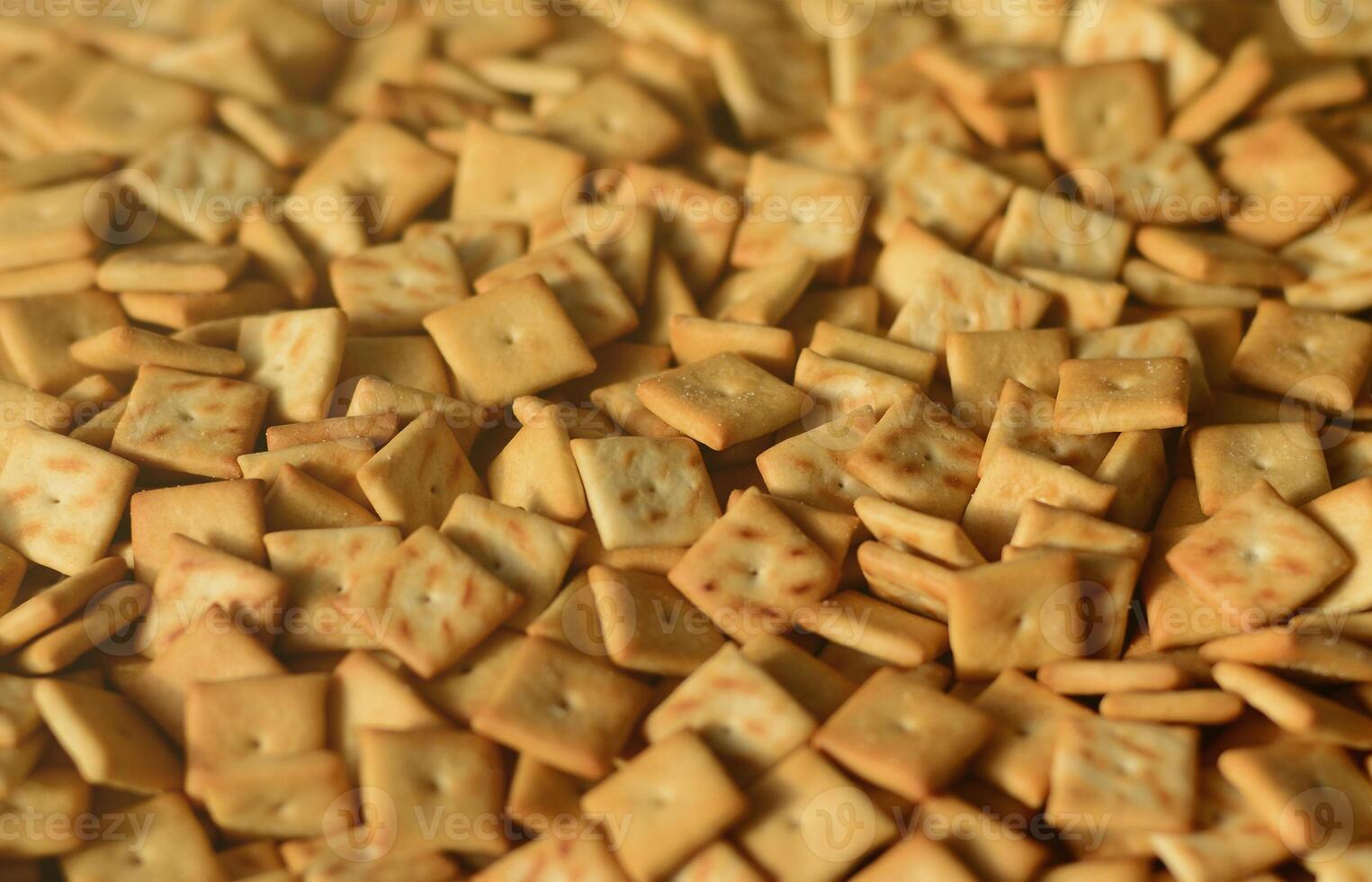 Background texture of small edible squares baked from dough and sprinkled with salt. A lot of salt cracker photo