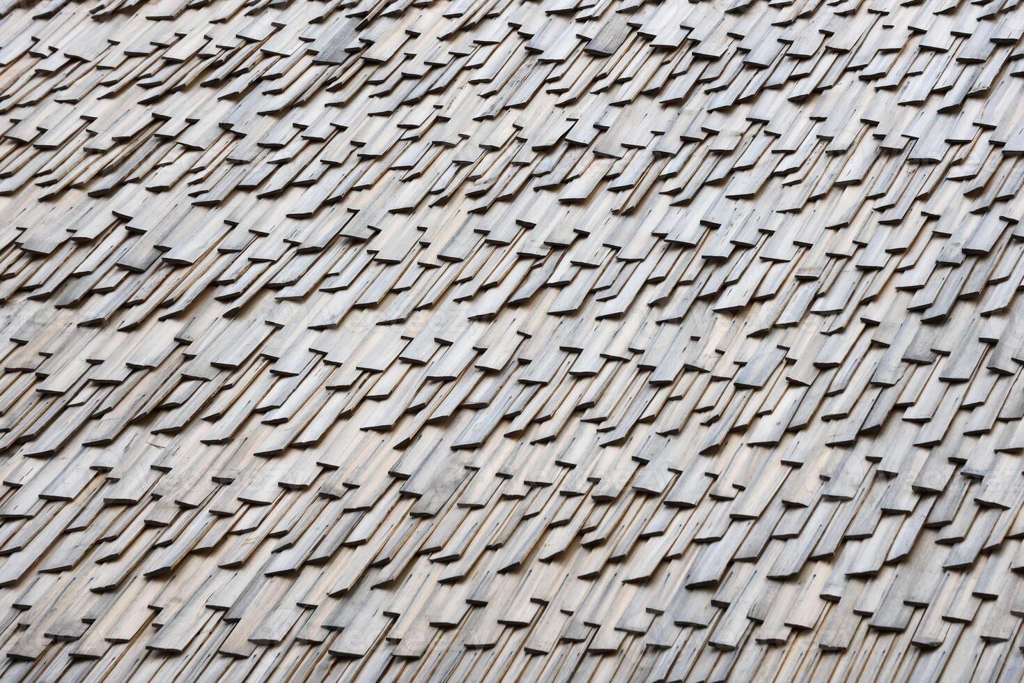 Gray wooden roof tiles background texture. A close up of old gray roof covered with wooden tiles photo