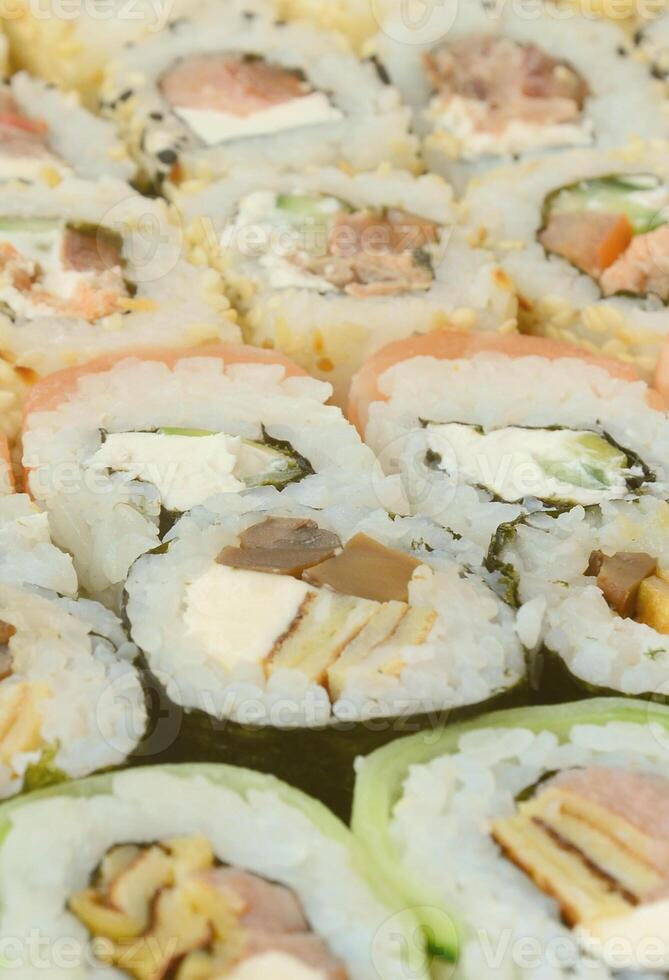 primer plano de muchos rollos de sushi con diferentes rellenos. toma macro de comida japonesa clásica cocinada. imagen de fondo foto