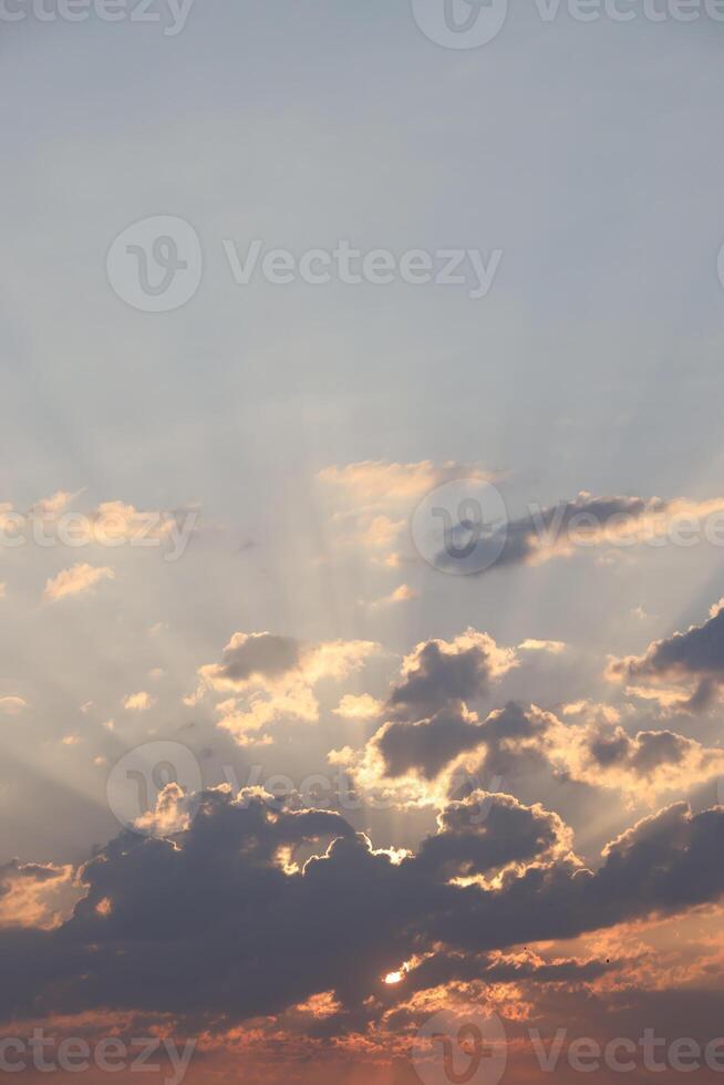 Beautiful sunrise with warm orange sunlight and beams through blue sky photo