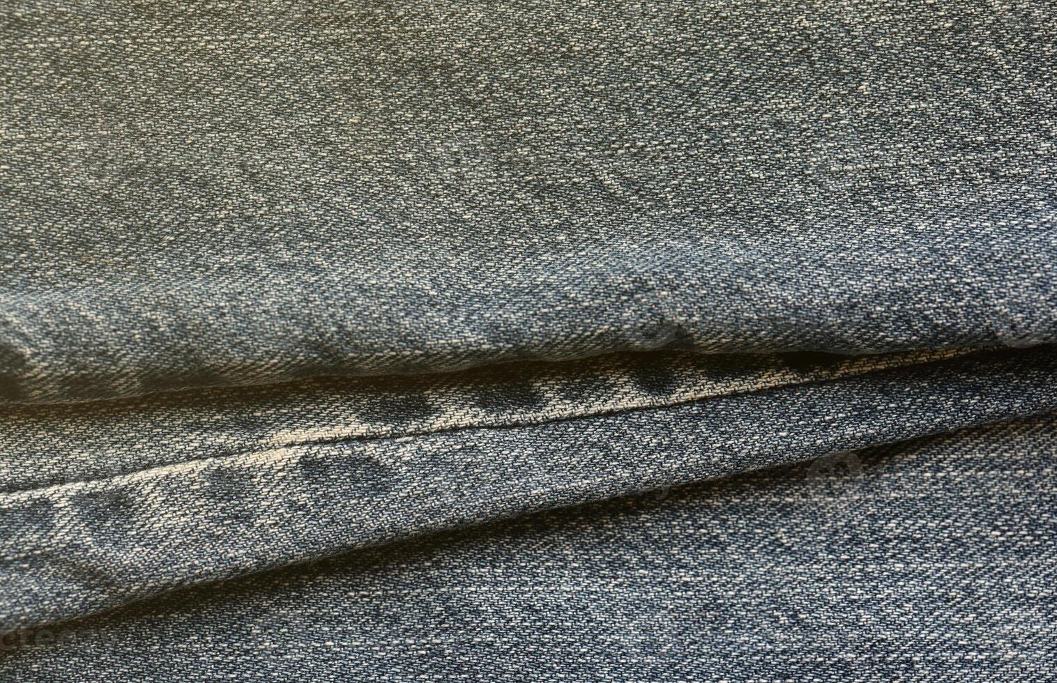 Detailed abstract texture of dark blue denim cloth. Background image of old used denim trousers fabric photo