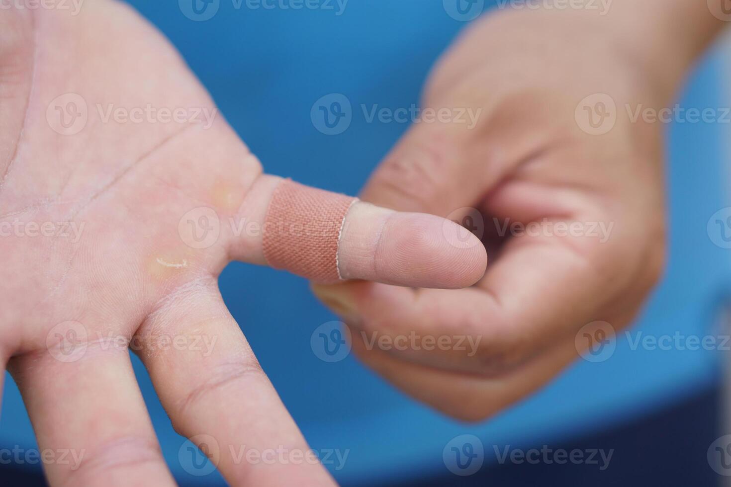 Close up man uses adhesive bandage tape to cover wound on finger. Concept, first aid. Self care for injury, to protect and prevent from dirt or germs into wound by covering adhesive bandage plaster. photo