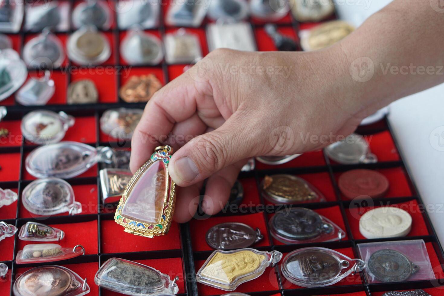Closeup hand holds Thai Buddha amulet from amulet collection. Concept, faith and belief for Buddhist for holy and luck. Colleting amulet as hobbies, exchange, selling or buying photo
