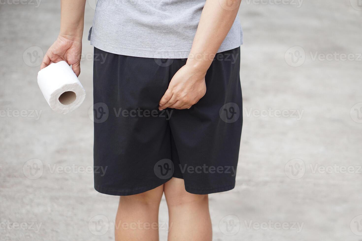 Close up woman holds tissue paper roll and hand touch her bottom. Concept, need to go to toilet. Diarrhea. Hemorrhoids. Health problems and health care. photo