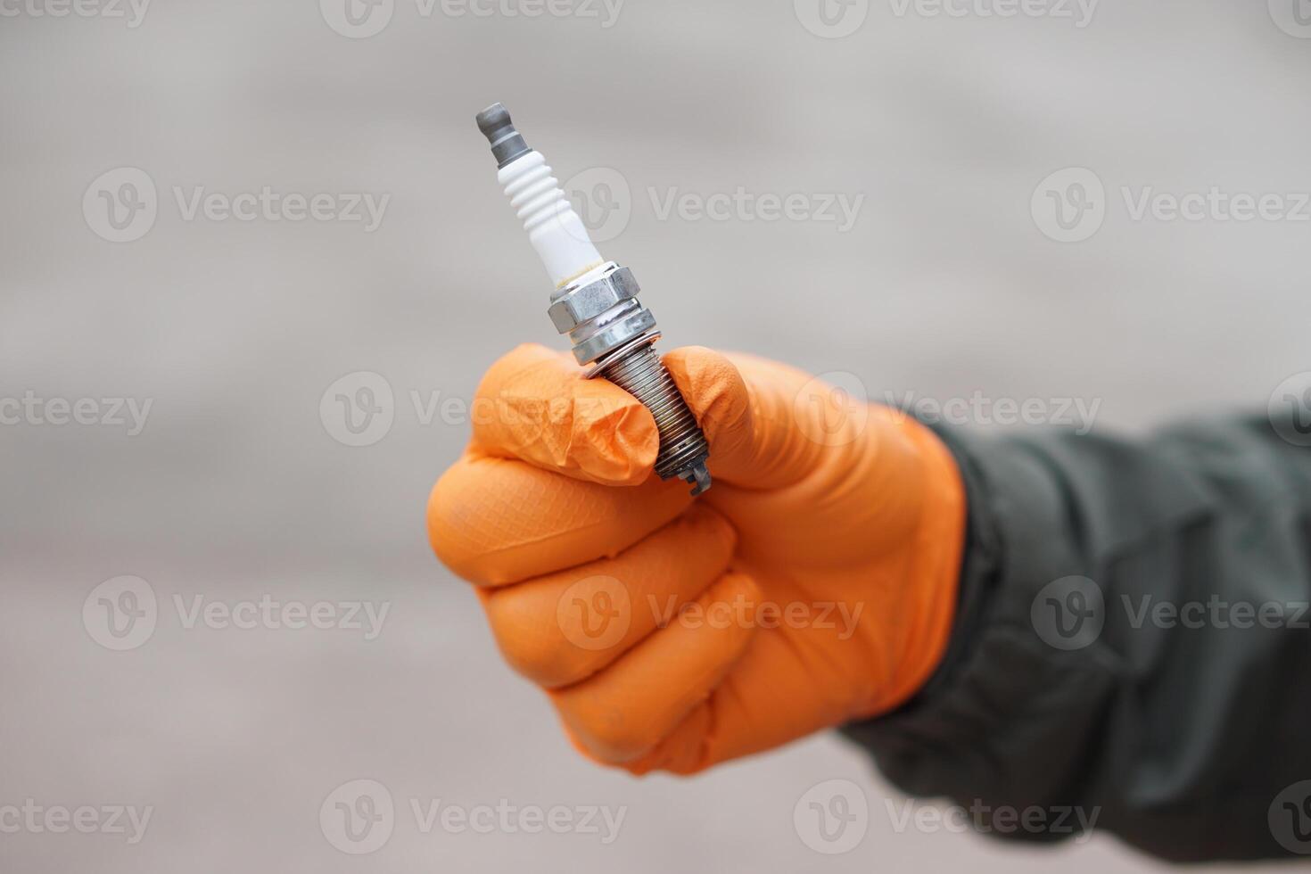 Close up mechanic hands hold old spark plug, spare part of car engine. Concept, machine maintenance, fix, repair, check or diagnose automobile problems by engine specialist. photo