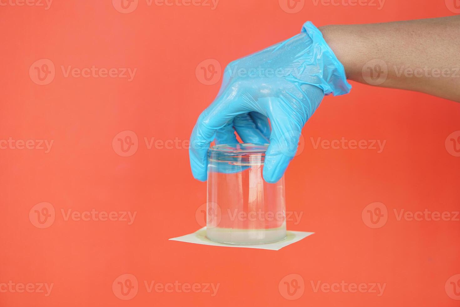 Closeup hand hold and turn a glass of water over down. covered the glass with paper. Concept, science experiment about air and liquid pressure. photo