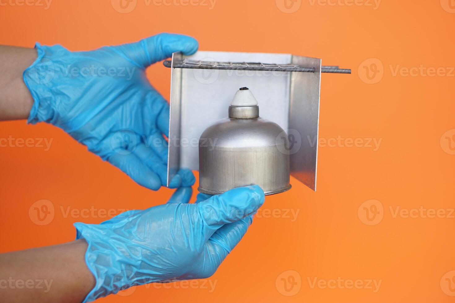 Close up hands wear blur gloves holds alcohol lamp and windshield. Equipment for doing science experiment. Concept, equipment or tool for science experiment. Educational toolkit in science subject. photo