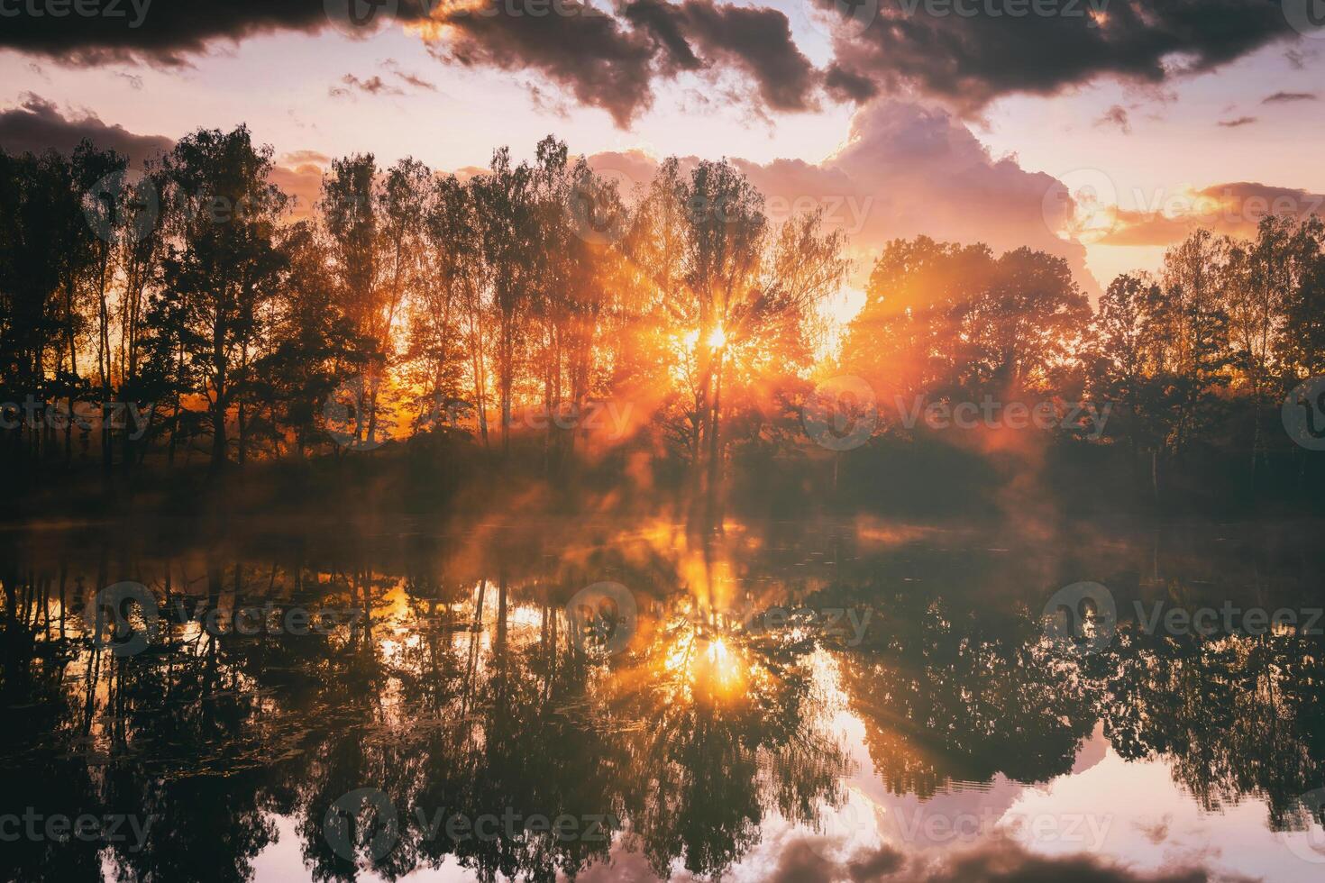 Dawn on a lake or river with a sky reflected in the water, birch trees on the shore and the sunbeams breaking through them and fog in autumn. Aesthetics of vintage film. photo