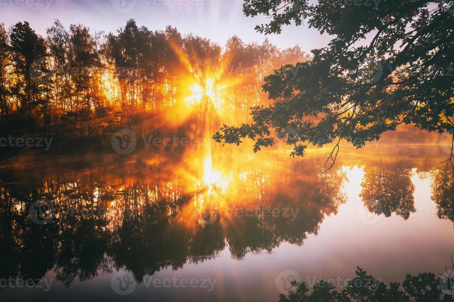 Dawn on a lake or river with a sky reflected in the water, birch trees on the shore and the sunbeams breaking through them and fog in autumn. Aesthetics of vintage film. photo