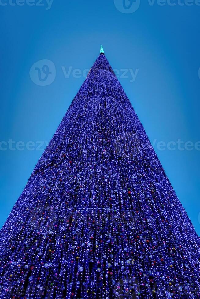 Artificial Christmas tree in garlands at twilight. photo