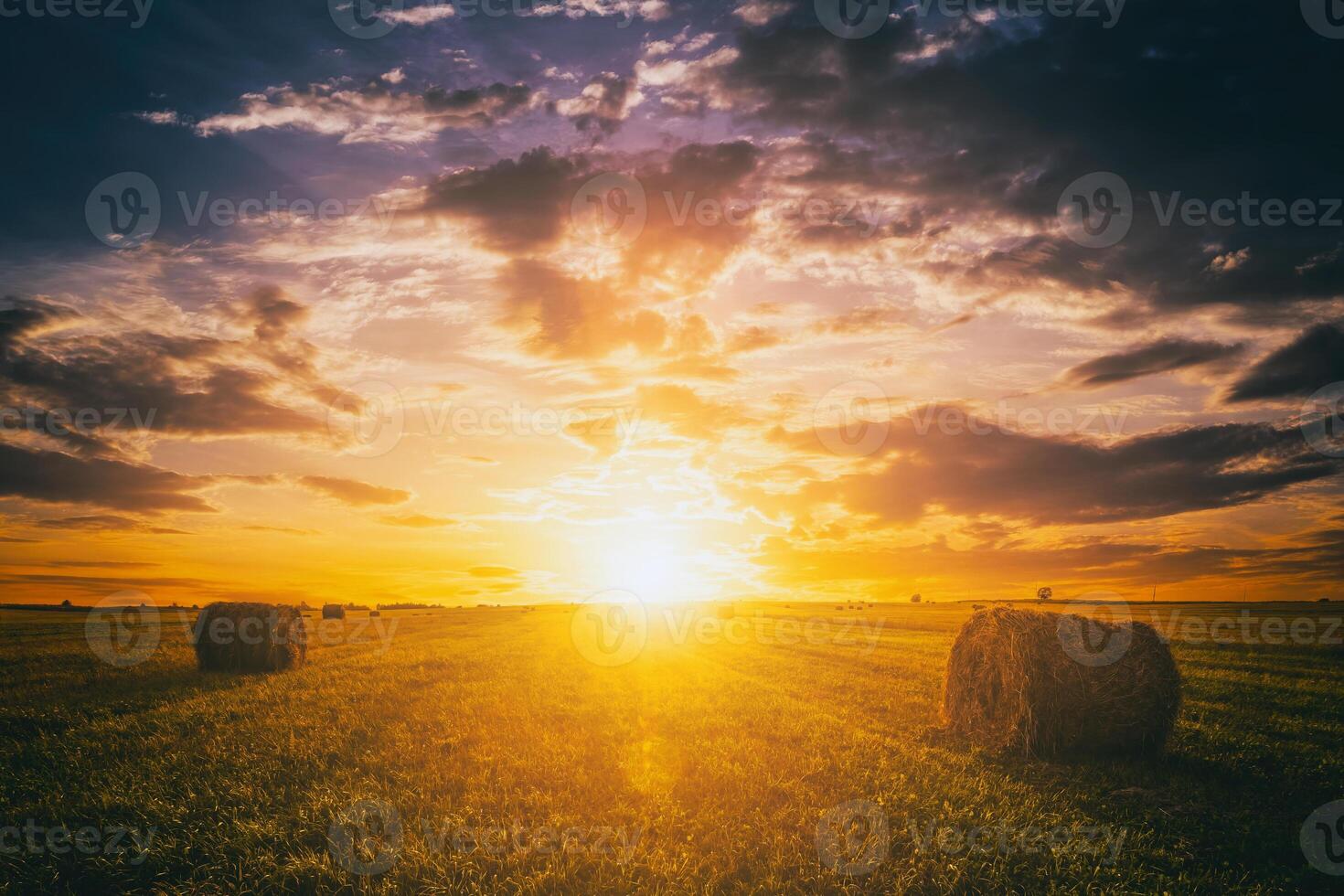 puesta de sol en un campo con pajar en un verano o temprano otoño noche con un nublado cielo en el antecedentes. obtención de animal alimentar en agricultura. Clásico película estético. foto