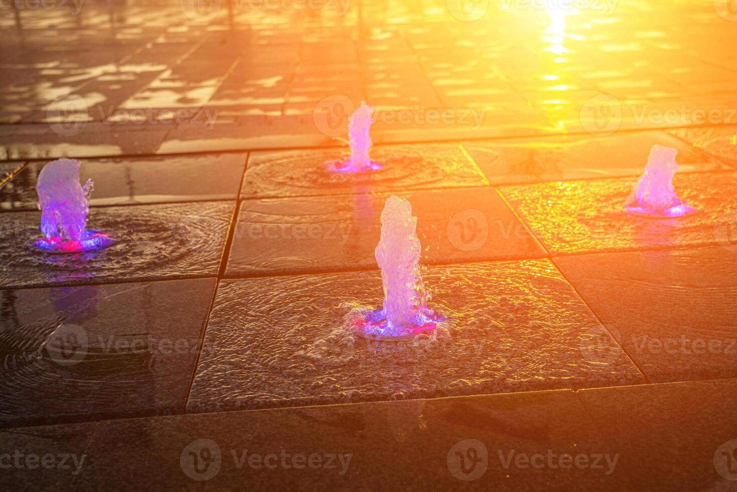 pequeño fuentes en el acera, iluminado por luz de sol a puesta de sol o amanecer a Hora de verano. foto