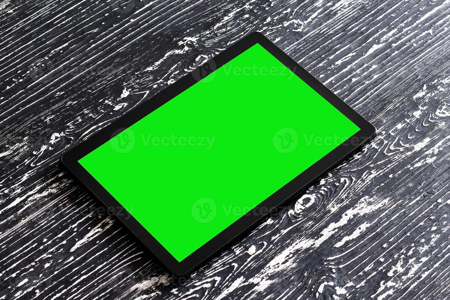 Black tablet with green screen on a wooden table mock up. Copy space chroma key display. photo