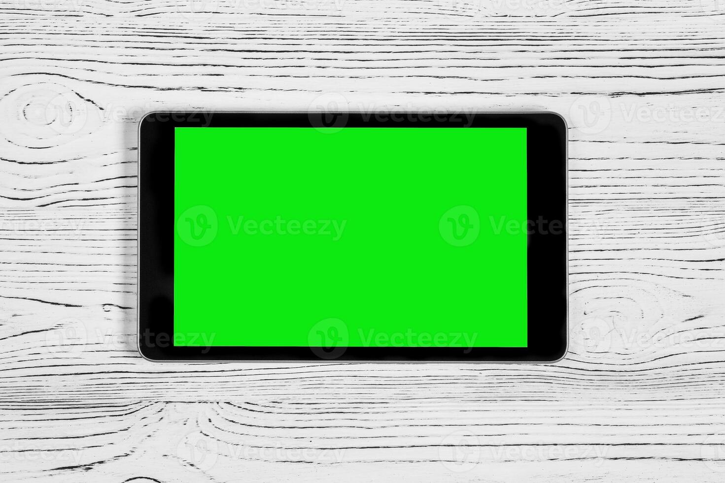 Black tablet with green screen on a wooden table mock up. Copy space chroma key display. photo