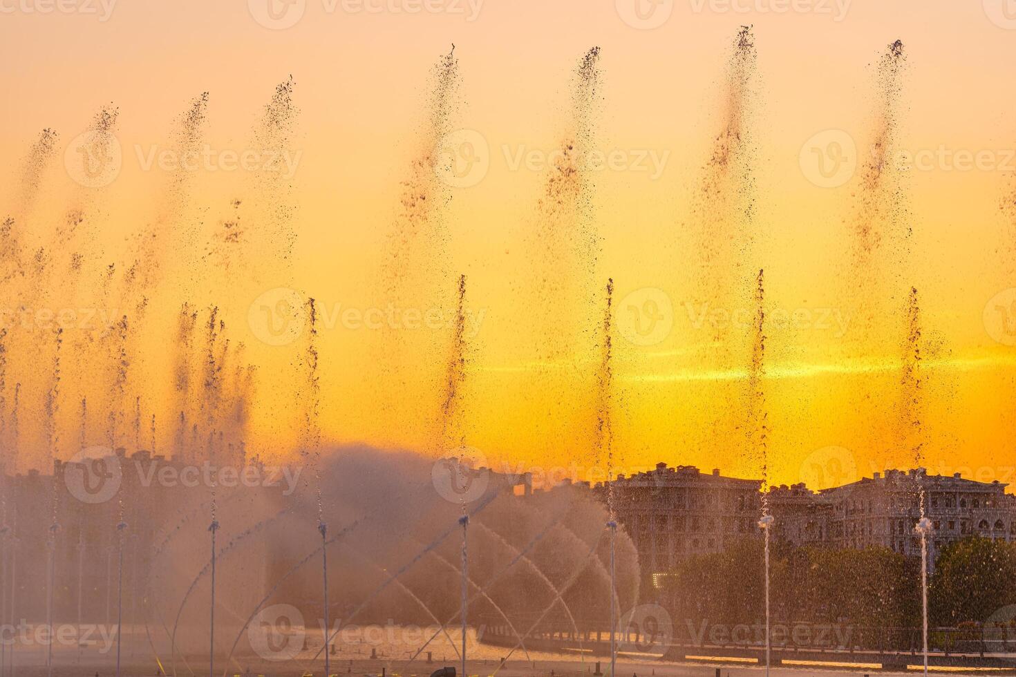 Big fountains on the artificial pond, illuminated by sunlight at sunset in Tashkent city park at summertime. photo