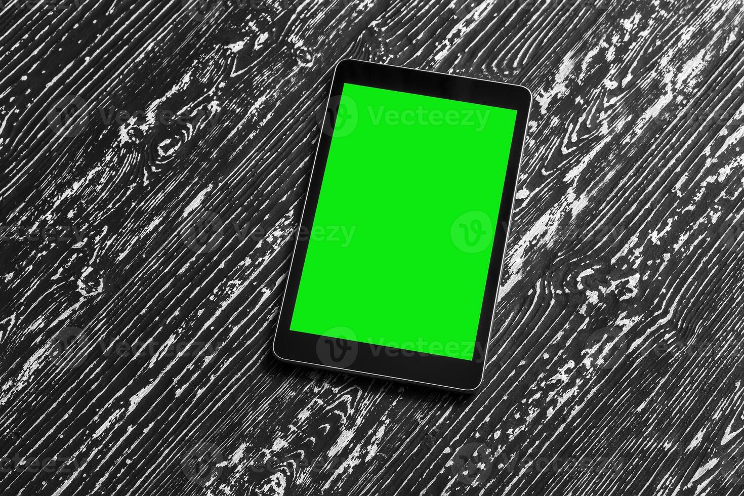 Black tablet with green screen on a wooden table mock up. Copy space chroma key display. photo