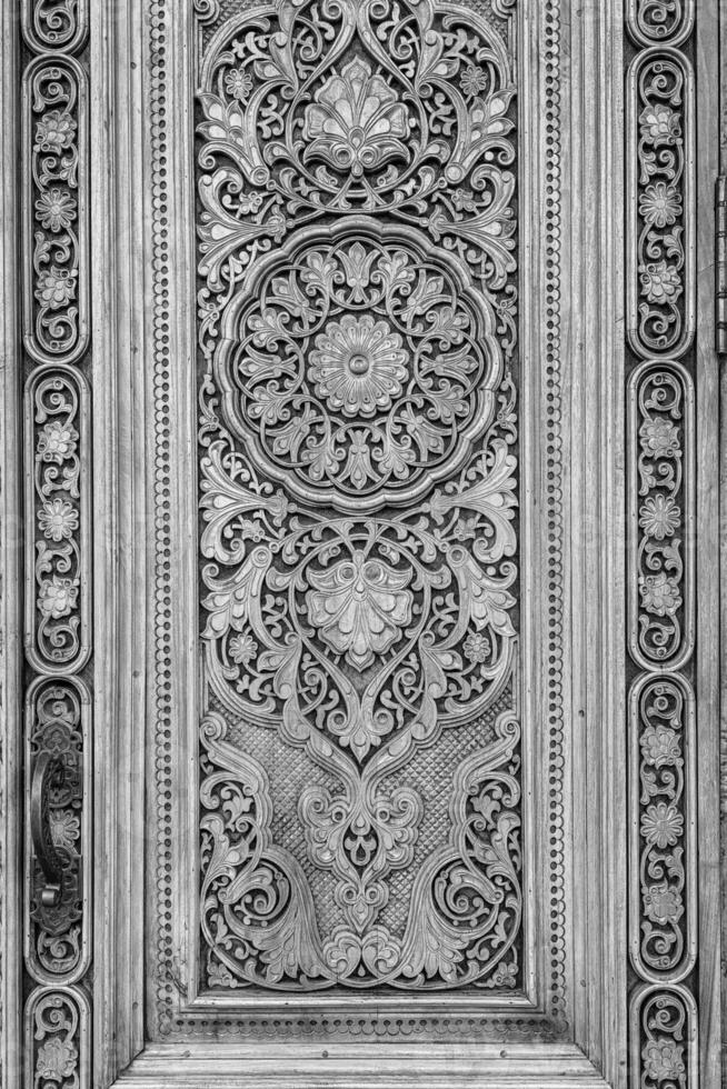 Black and white fragment of an ancient carved wooden door. Ornate. photo