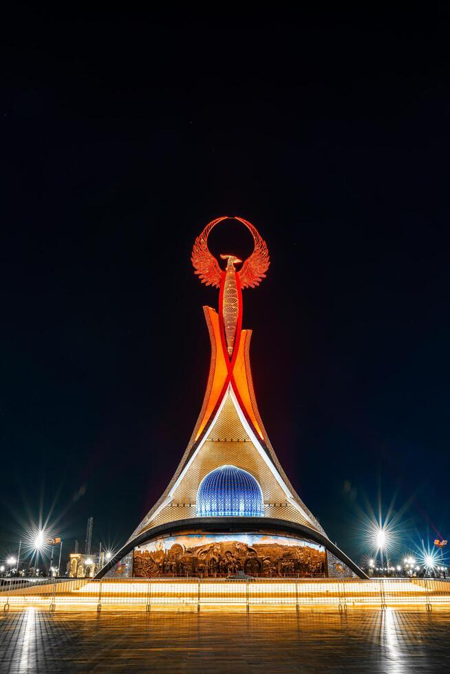 UZBEKISTAN, TASHKENT - APRIL 25, 2023 Illuminated monument of independence in the form of a stele with a Humo bird in the New Uzbekistan park at nighttime. photo