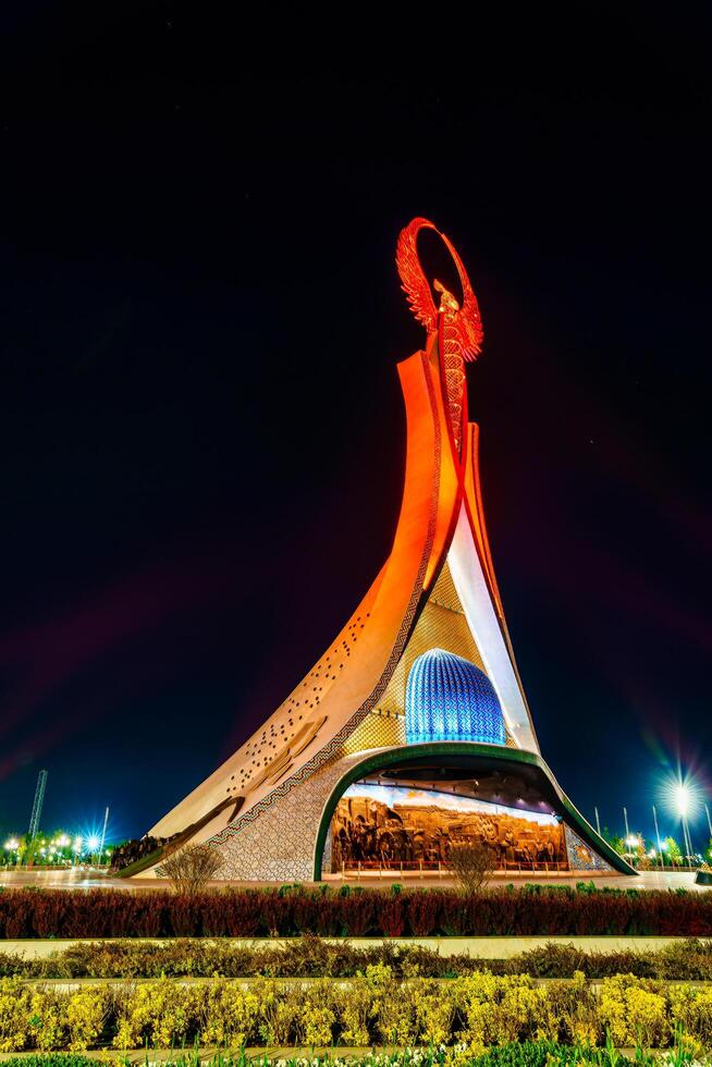 UZBEKISTAN, TASHKENT - APRIL 25, 2023 Illuminated monument of independence in the form of a stele with a Humo bird in the New Uzbekistan park at nighttime. photo