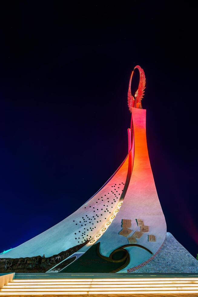 UZBEKISTAN, TASHKENT - APRIL 25, 2023 Illuminated monument of independence in the form of a stele with a Humo bird in the New Uzbekistan park at nighttime. photo