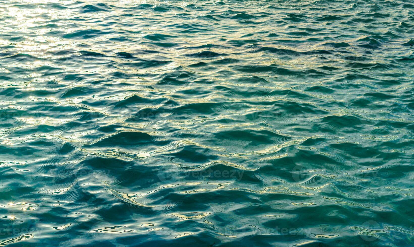 The texture of the waves in turquoise color, illuminated by the sun at sunset or dawn. Nature background. photo