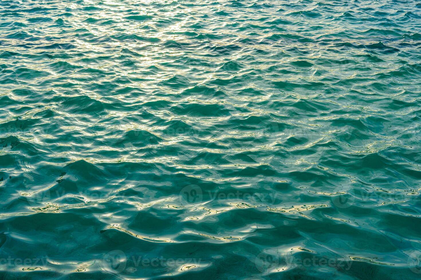 The texture of the waves in turquoise color, illuminated by the sun at sunset or dawn. Nature background. photo