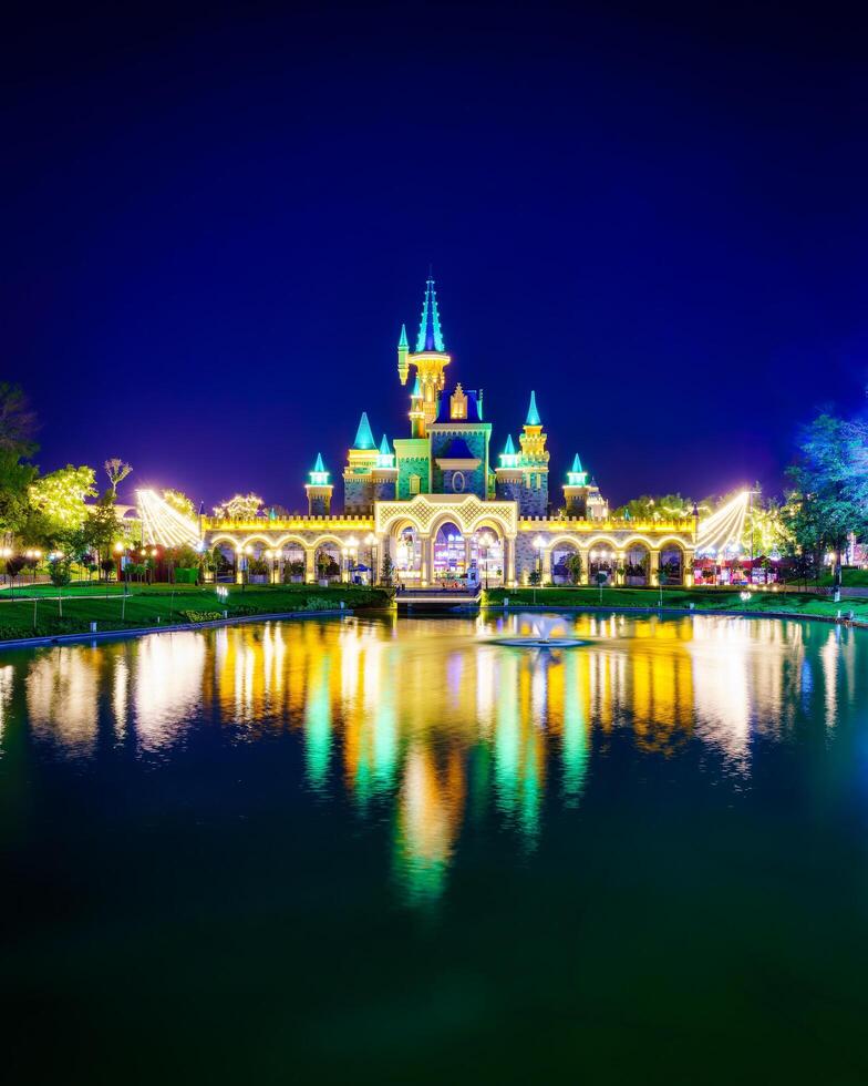 TASHKENT, UZBEKISTAN - APRIL 20, 2023 Magic City amusement park on evening reflected in a water. photo