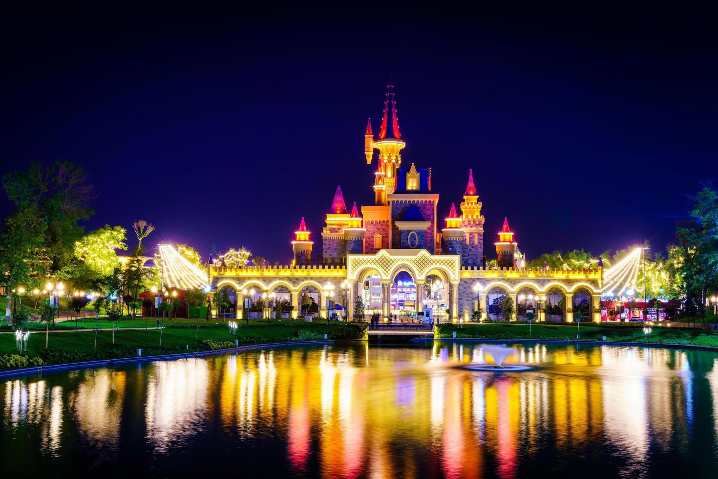 TASHKENT, UZBEKISTAN - APRIL 20, 2023 Magic City amusement park on evening reflected in a water. photo