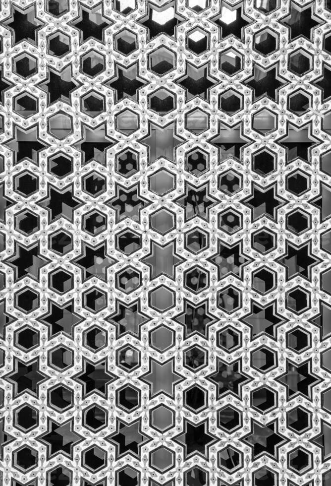 negro y blanco el ventana de un musulmán mezquita detrás barras en el formar de un geométrico hexagonal islámico ornamento. foto