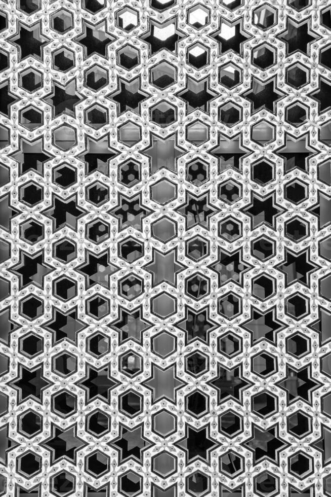 negro y blanco el ventana de un musulmán mezquita detrás barras en el formar de un geométrico hexagonal islámico ornamento. foto