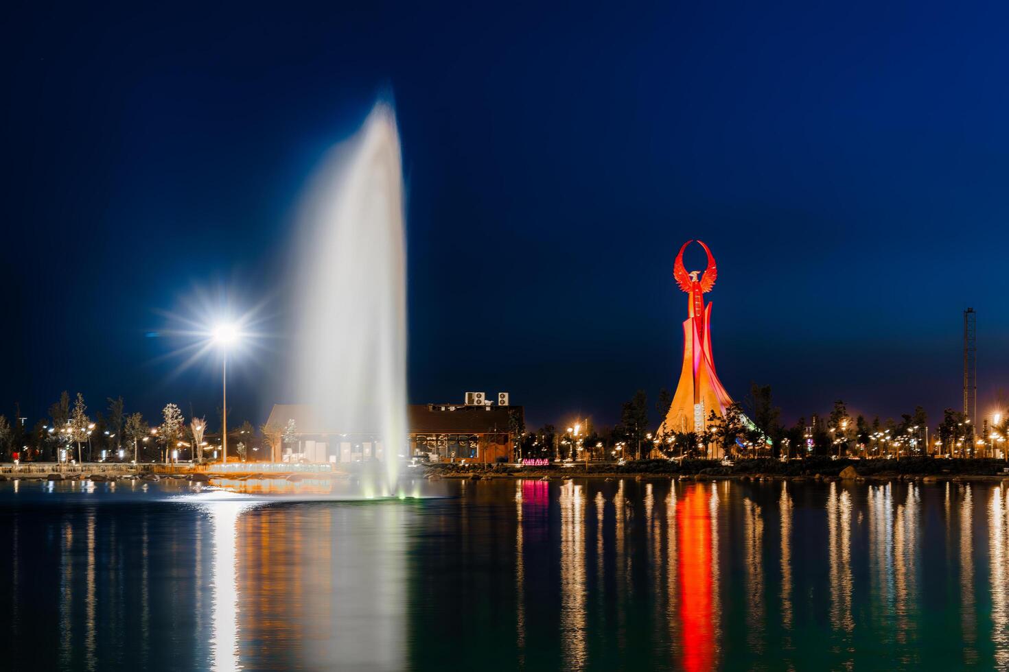 UZBEKISTAN, TASHKENT - APRIL 25, 2023 Illuminated monument of independence in the form of a stele with a Humo bird and fountain in the New Uzbekistan park at nighttime. photo