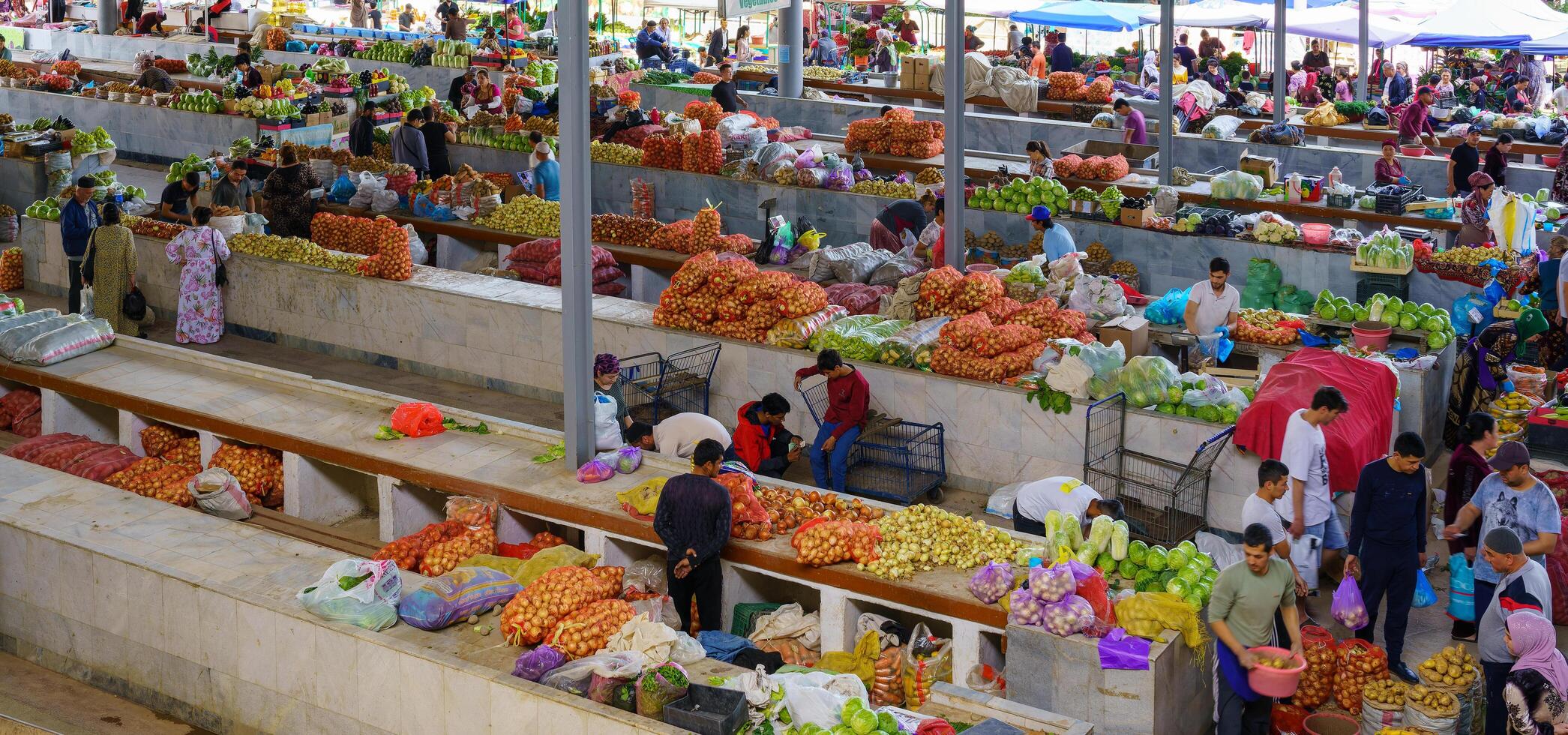 Samarkand, Uzbekistan - April 27, 2023 Top view of rows of fruit and vegetable stalls and vendors in an oriental bazaar in central Asia. photo