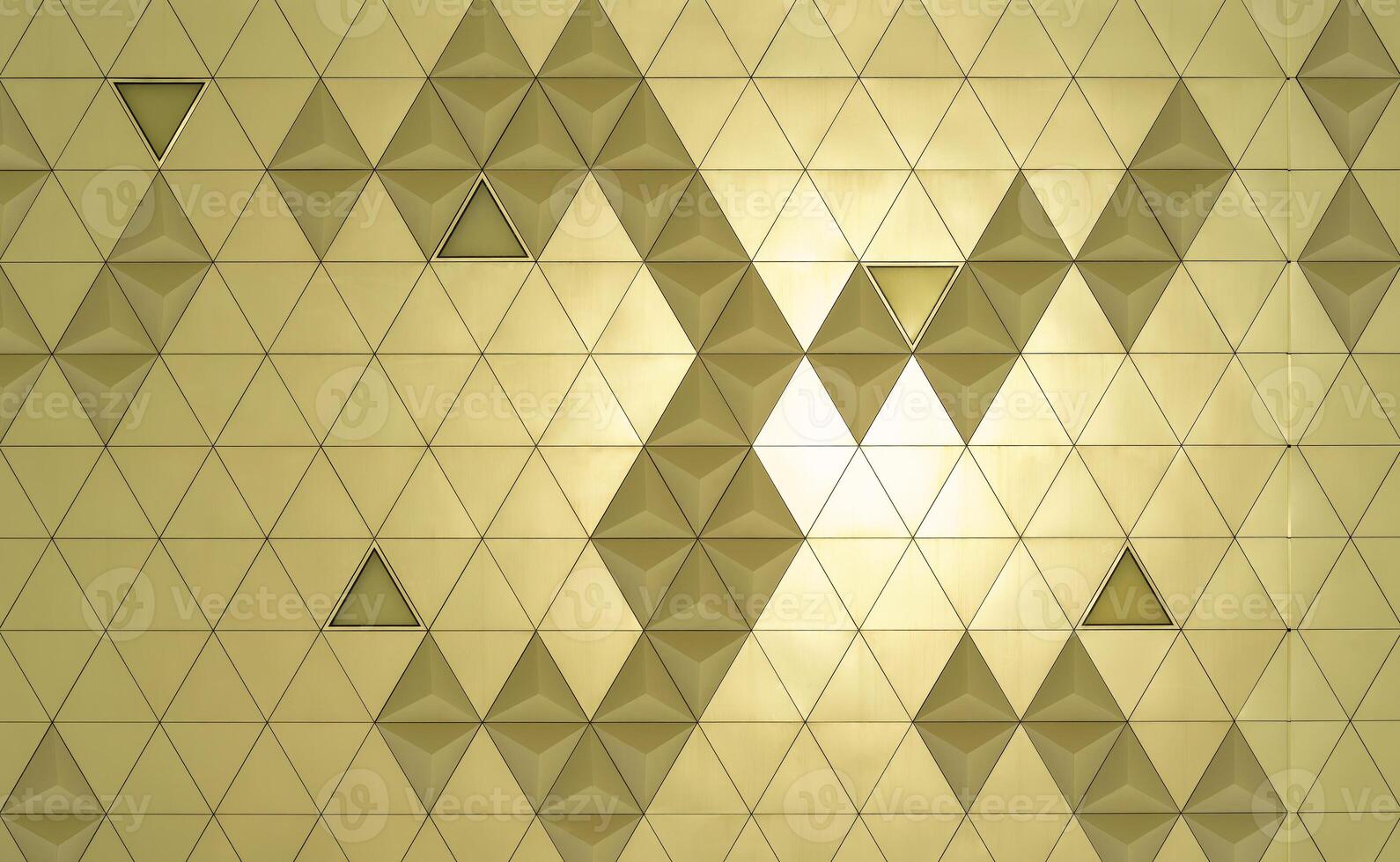 Golden diamond-shaped polished metal cladding panels of a modern building illuminated by sunlight. Abstract background. photo