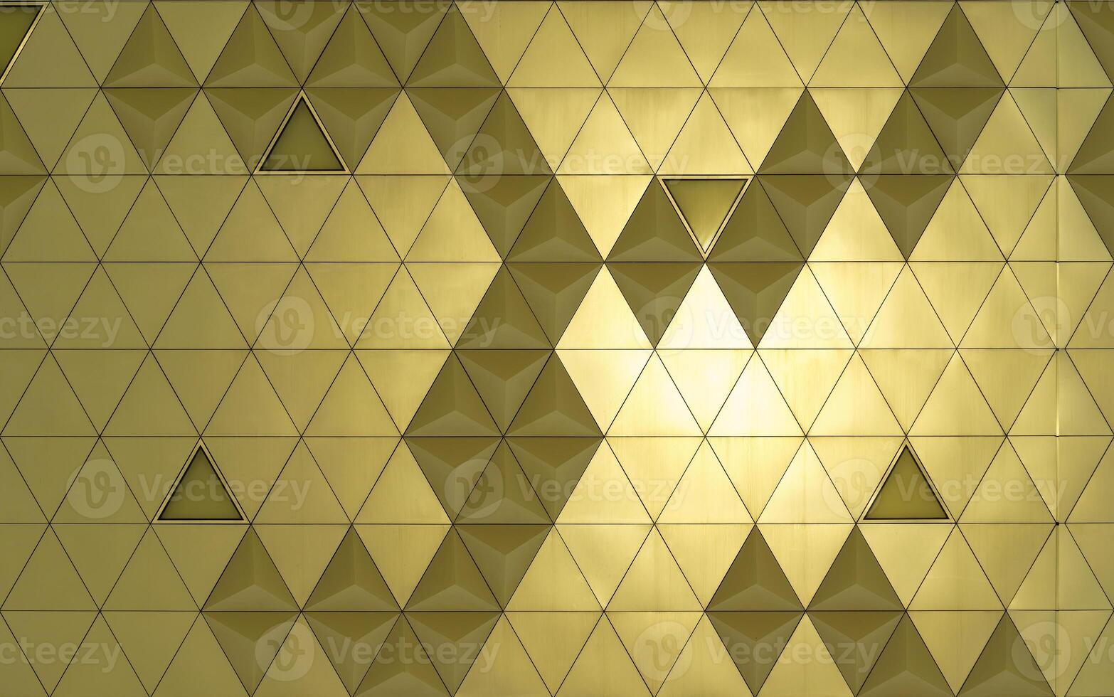 Golden diamond-shaped polished metal cladding panels of a modern building illuminated by sunlight. Abstract background. photo