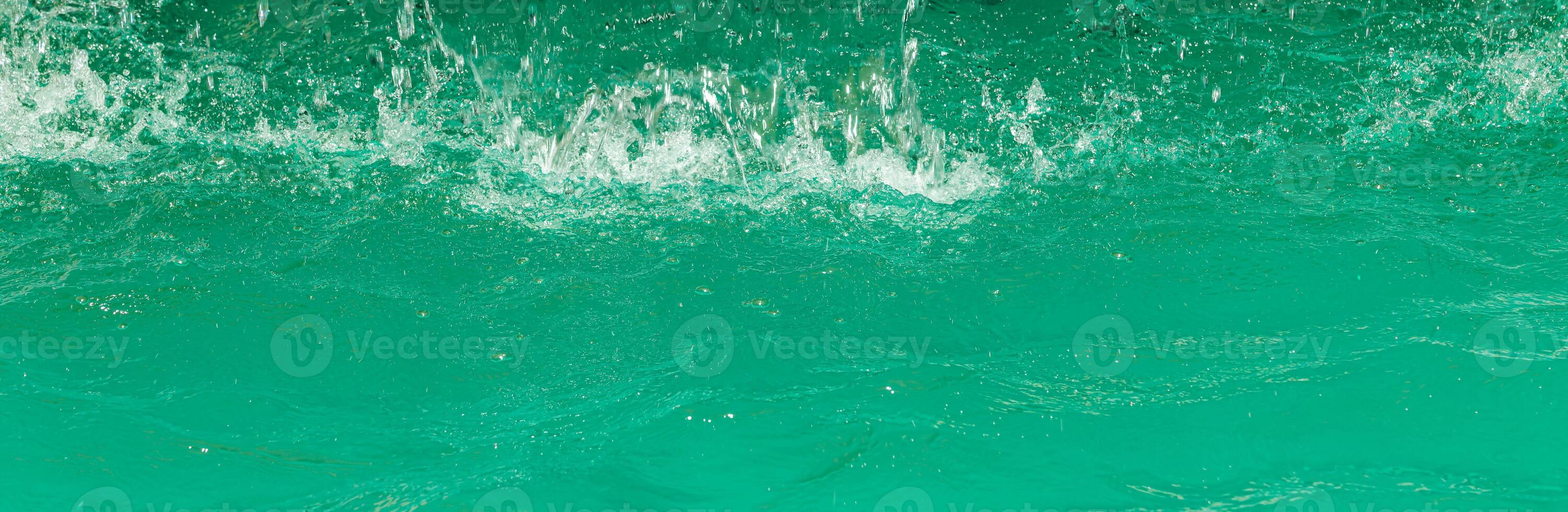 Turquoise flow of falling water and splashes from it, illuminated by sunlight. Nature background. photo