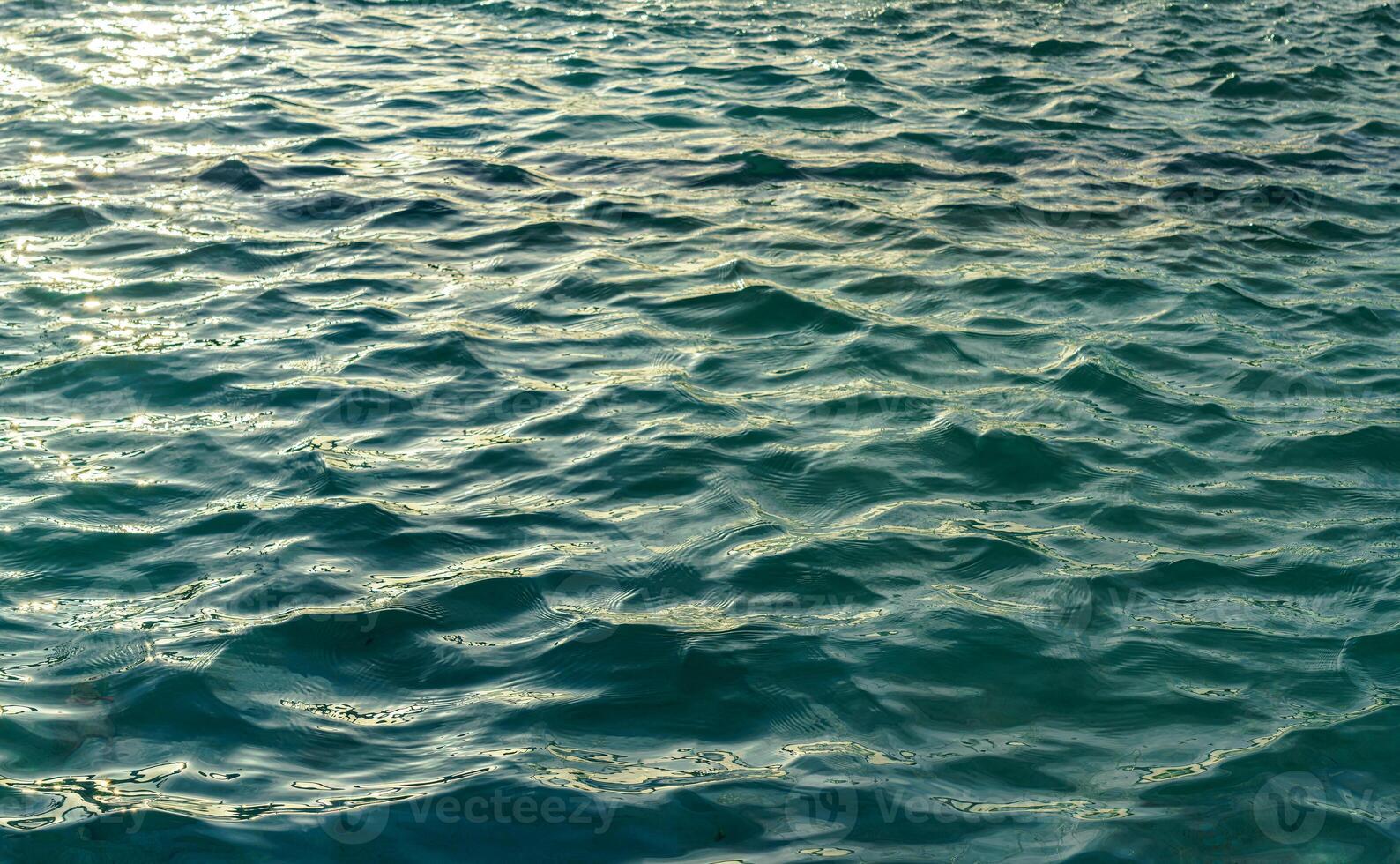 el textura de el olas en turquesa color, iluminado por el Dom a puesta de sol o amanecer. naturaleza antecedentes. foto