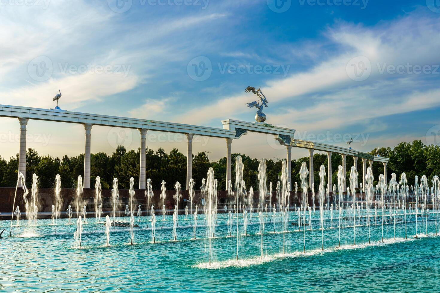 monumento y filas de fuentes iluminado por luz de sol a puesta de sol o amanecer en el independencia cuadrado a Hora de verano, Taskent. foto