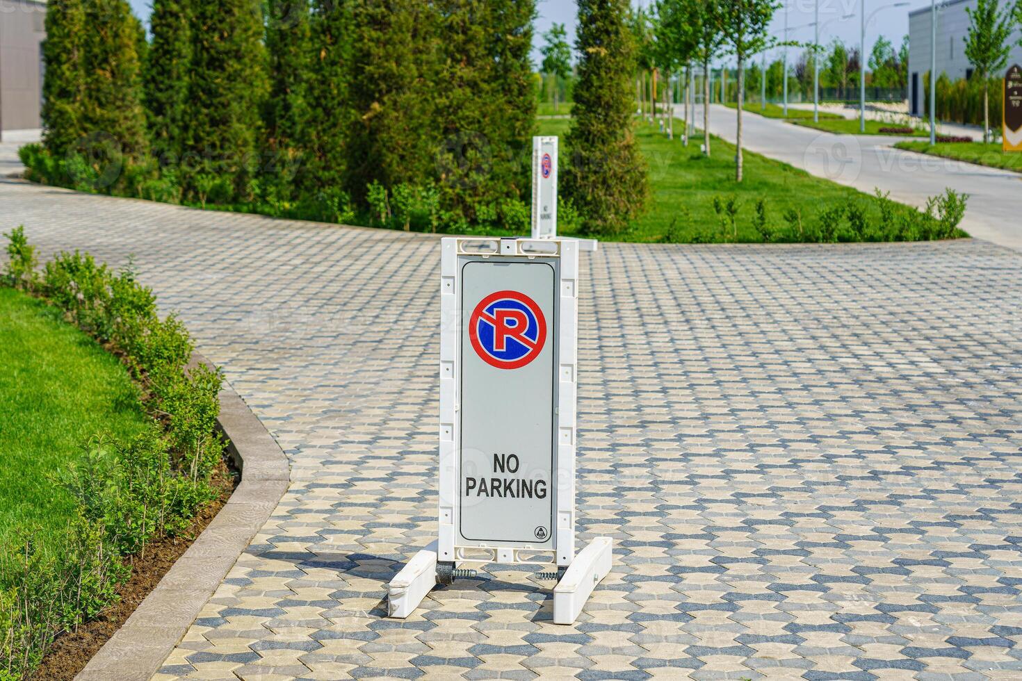 A sign with a sign not to park standing on a stone pavement. photo