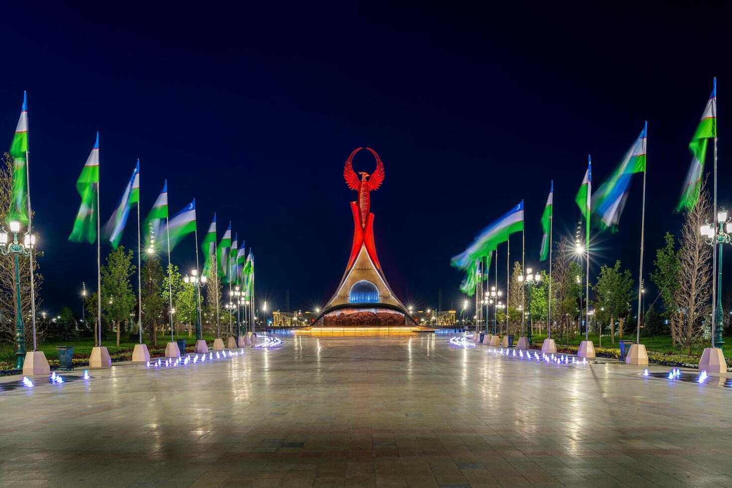 UZBEKISTAN, TASHKENT - MAY 5, 2023 Illuminated monument of independence in the form of a stele with a Humo bird, fountains and waving flags in the New Uzbekistan park at nighttime. photo