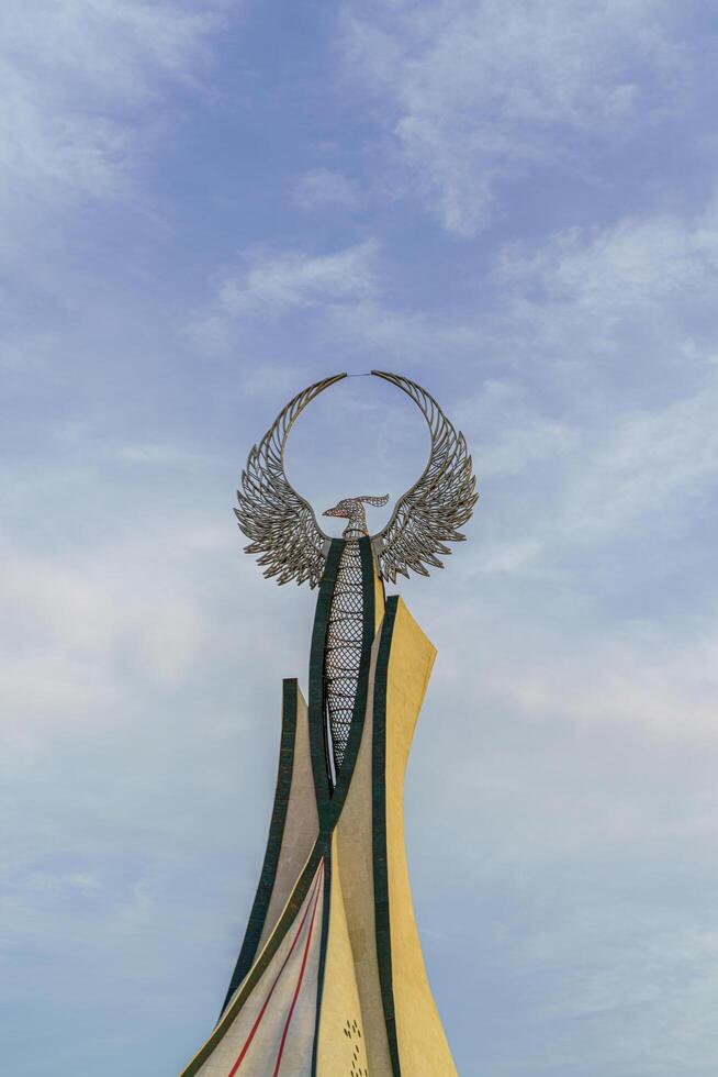 UZBEKISTAN, TASHKENT - MAY 25, 2023 Monument of Independence in the form of a stele with a Humo bird against a cloudy sky in the New Uzbekistan park. photo