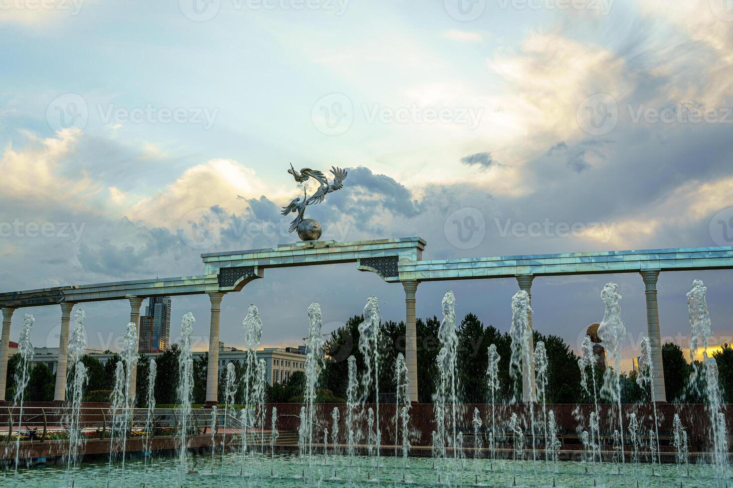 monumento y filas de fuentes iluminado por luz de sol a puesta de sol o amanecer en el independencia cuadrado a Hora de verano, Taskent. foto